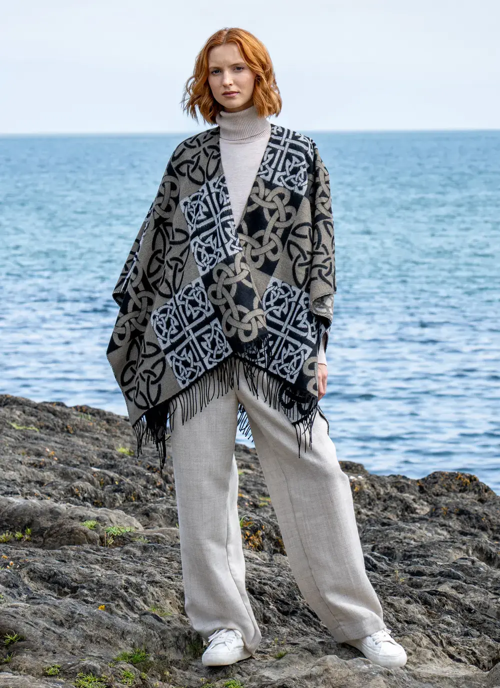Red head model standing in front of water in black celtic knot shawl